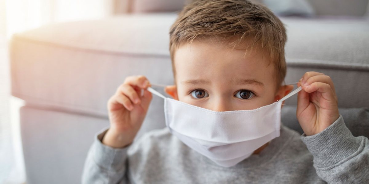 A young boy pulling a mask over his face